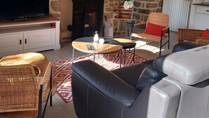 Ein gemütliches Wohnzimmer mit Steinwand, Kamin, Fernseher und bequemen Sitzmöglichkeiten.