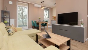 Un salon moderne comprenant un canapé, une table basse, un téléviseur et un coin repas avec des chaises et une table.