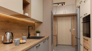 Une cuisine moderne dotée de plans de travail en bois, d’une bouilloire en acier inoxydable, d’un évier et d’un réfrigérateur.