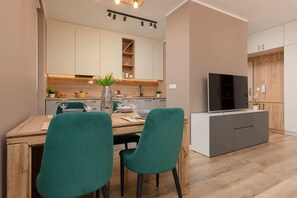Une cuisine moderne avec un coin repas, des meubles en bois, un téléviseur et une petite plante.