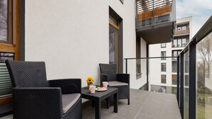 Un balcon agrémenté de meubles en osier, d’une petite table et d’un vase rempli de fleurs.