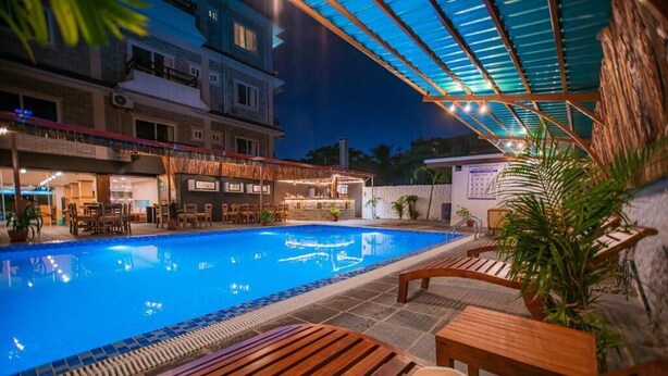 Una piscina con tumbonas de madera y una zona de bar.
