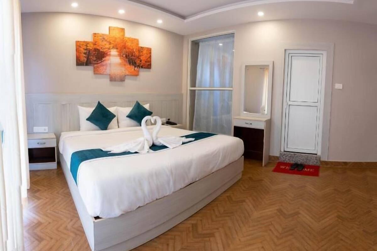 Une chambre spacieuse avec un grand lit, une table de chevet, un miroir et une porte.
