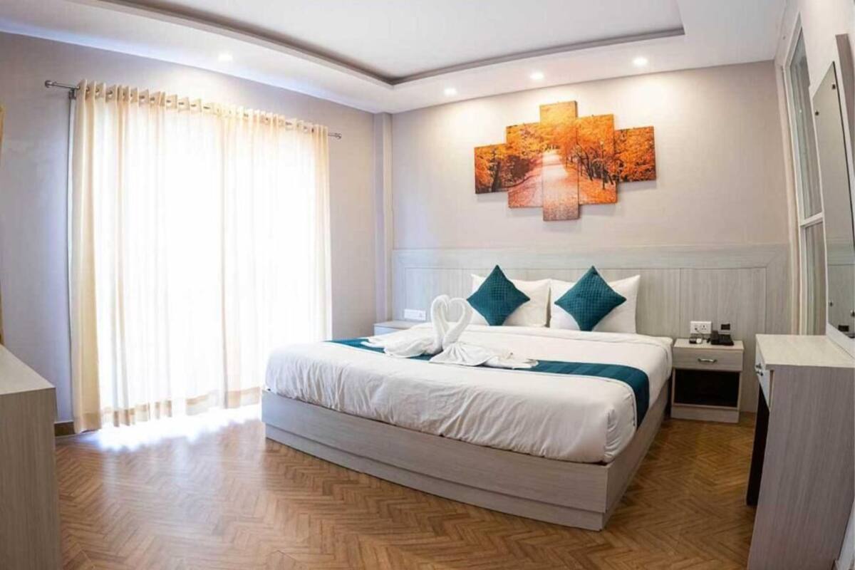 Une chambre d’hôtel avec un grand lit, une table de chevet, une commode et une œuvre d’art accrochée au mur.