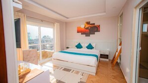 Una habitación de hotel moderna con una cama grande, un escritorio y vistas de la ciudad desde el balcón.