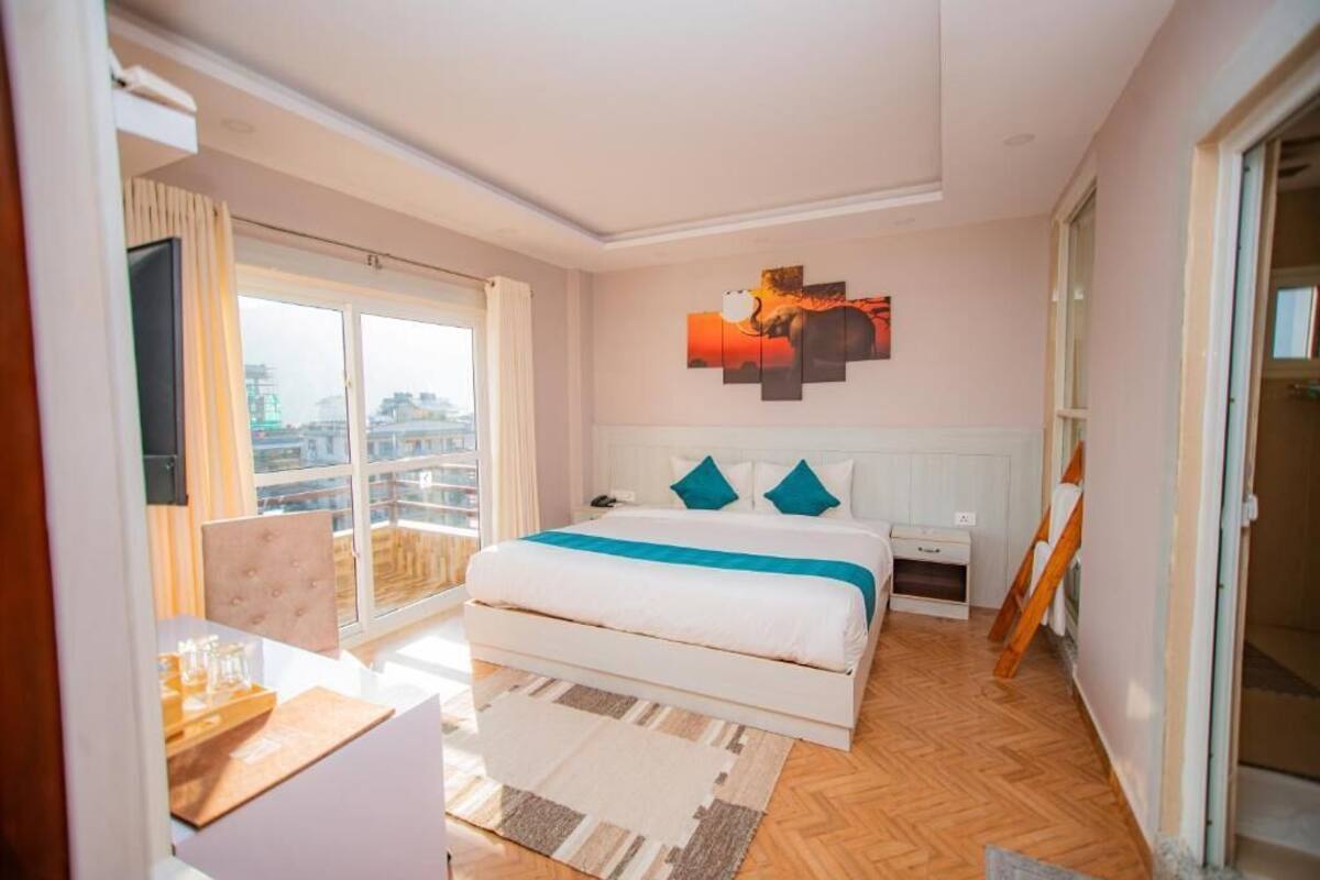 Une chambre d’hôtel moderne dotée d’un grand lit, d’un bureau et offrant une vue sur la ville depuis le balcon.