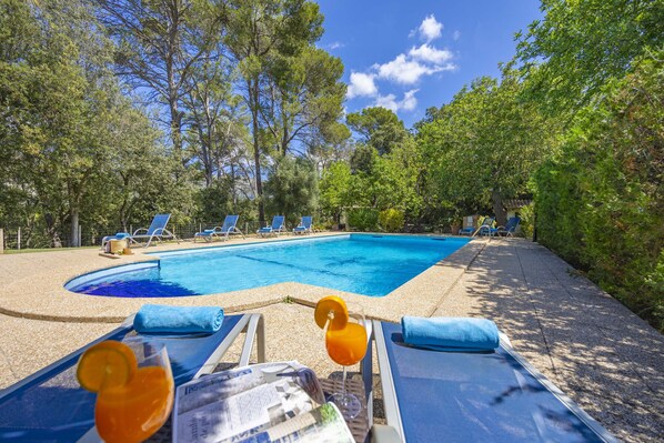 A swimming pool with lounge chairs and a drink on the deck.