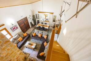 Amplia sala de estar con un conjunto de sofás, una mesa de comedor y una escalera.