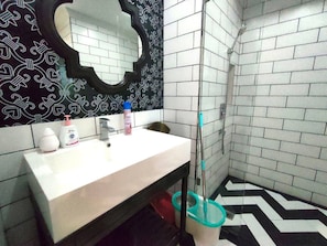 A bathroom with a white sink, a mirror, and a shower area.
