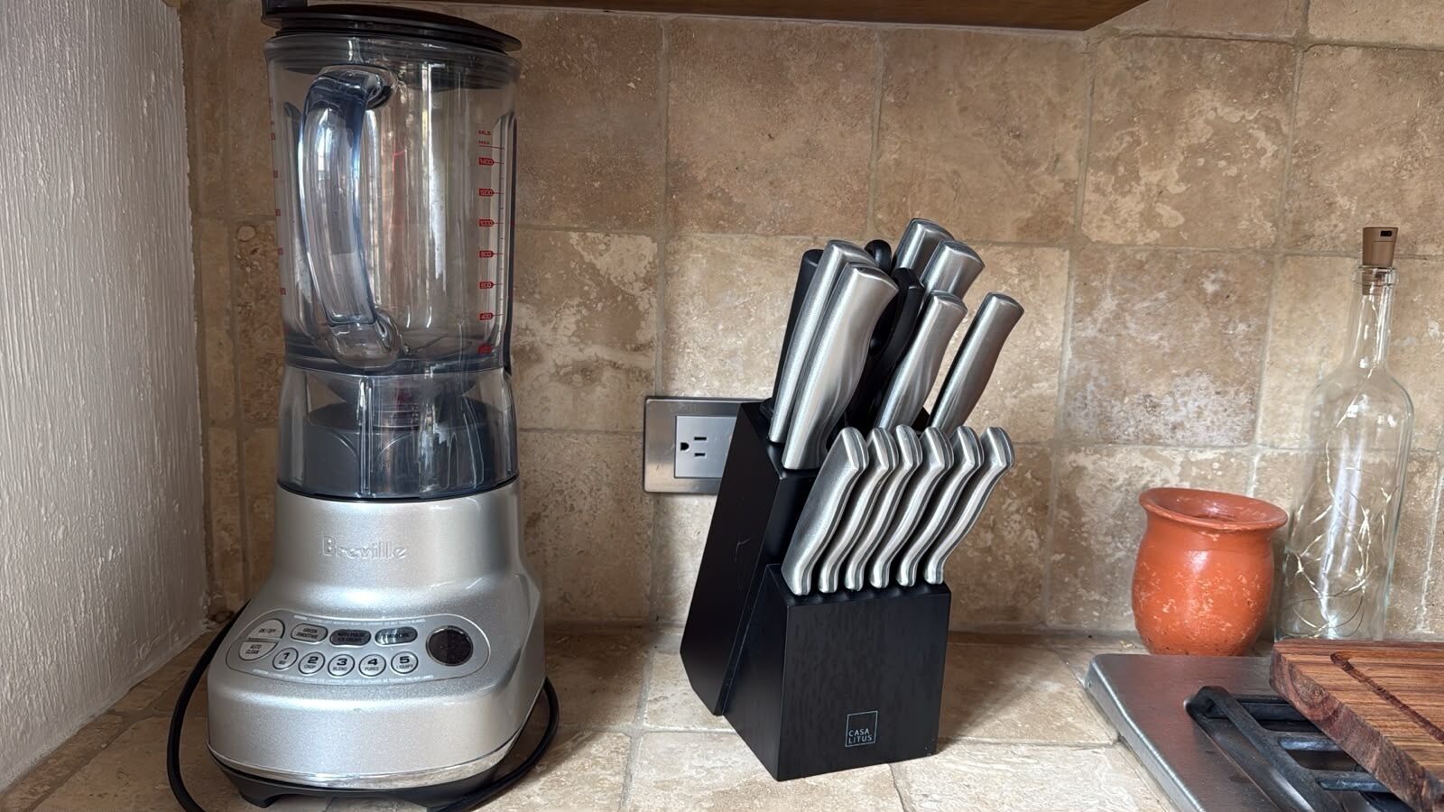 Een keuken met een blender, messenblok en een terracotta pot.
