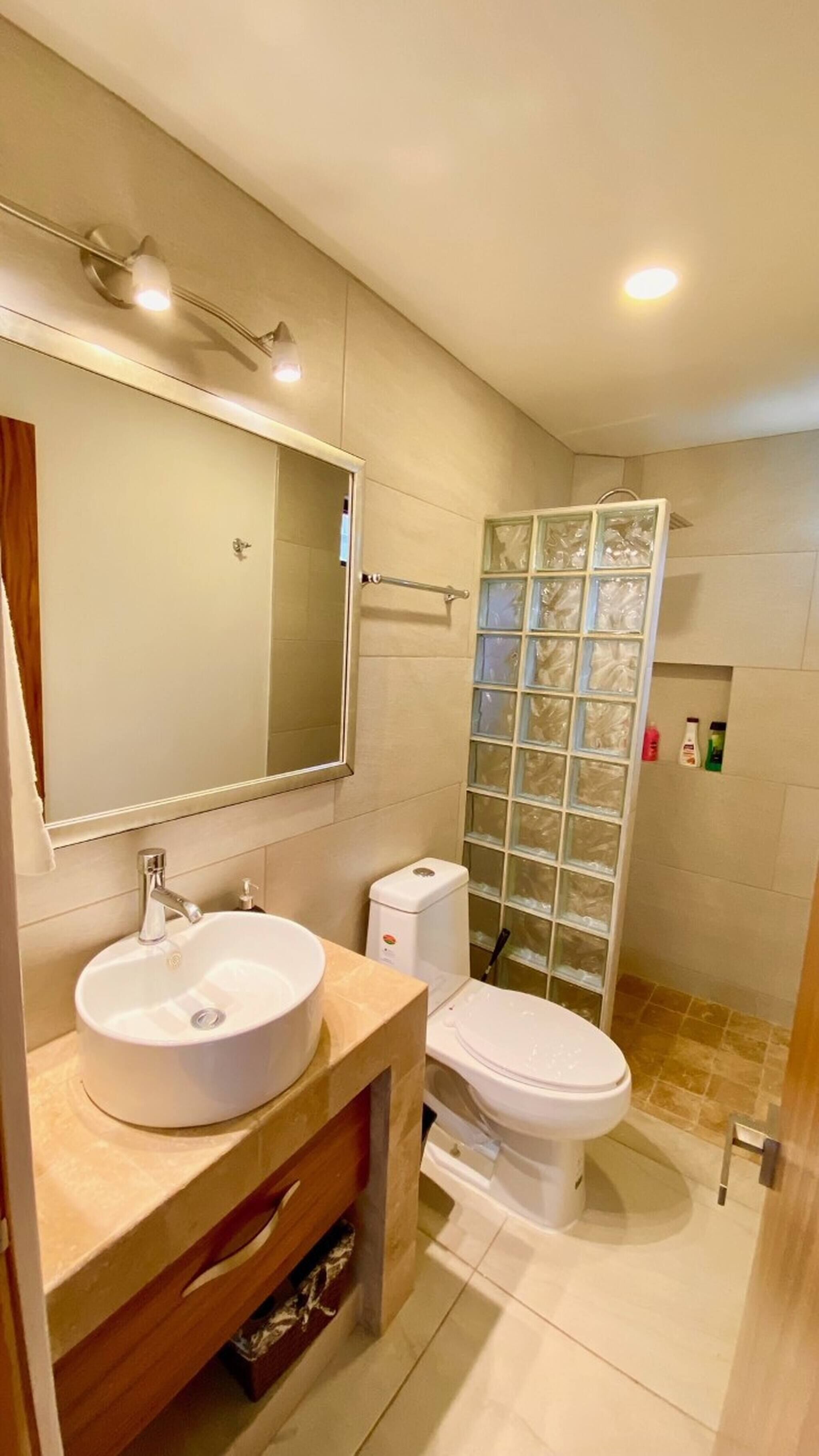 Et moderne badeværelse med vask, toilet og brusekabine i glas.