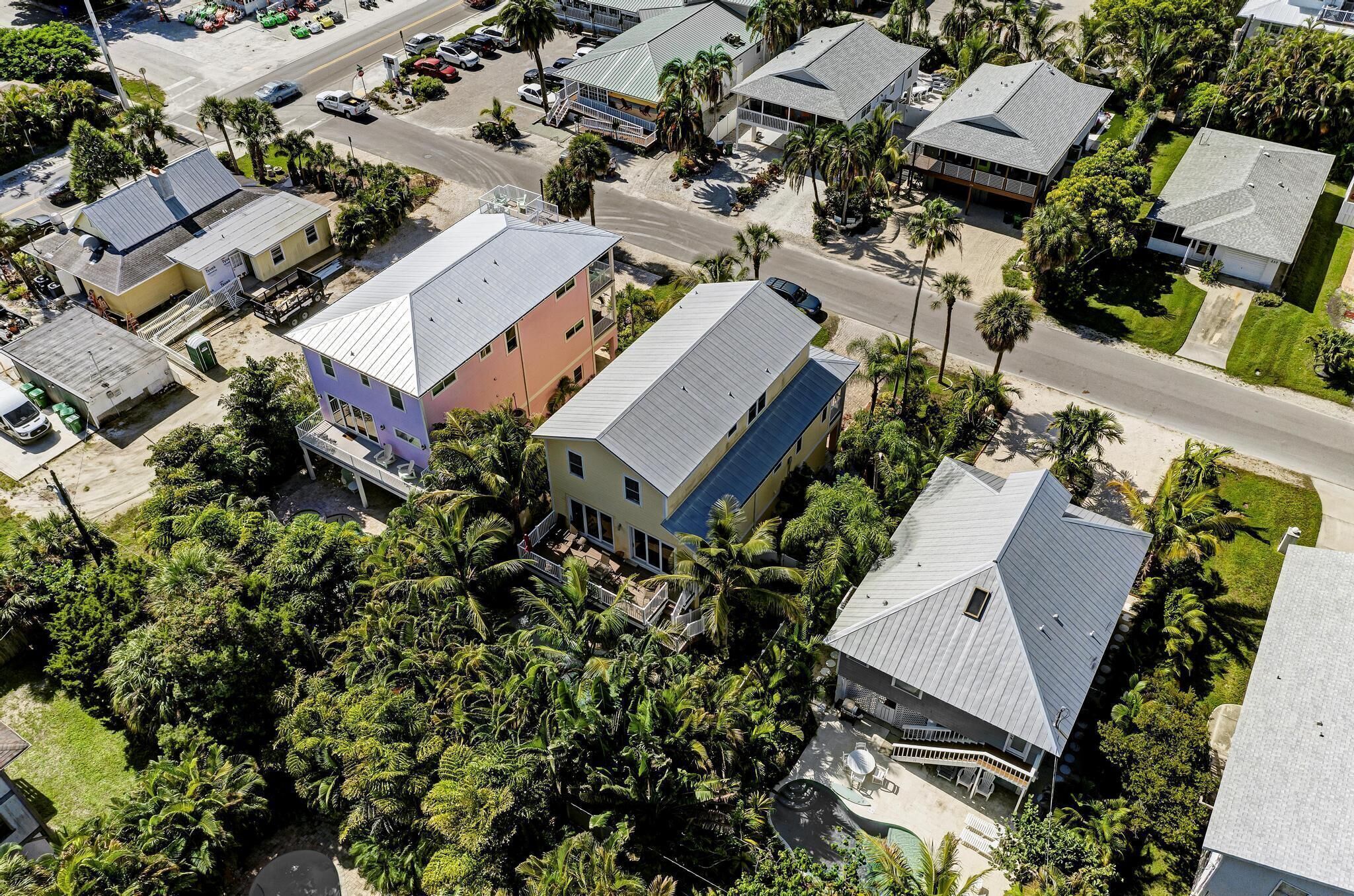 An aerial view of a residential area with houses, roads, and palm trees.