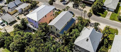 An aerial view of a residential area with houses, roads, and palm trees.