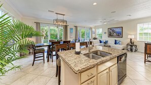 A spacious kitchen with granite countertops, a built-in dishwasher, and a dining area with wooden chairs and a table.