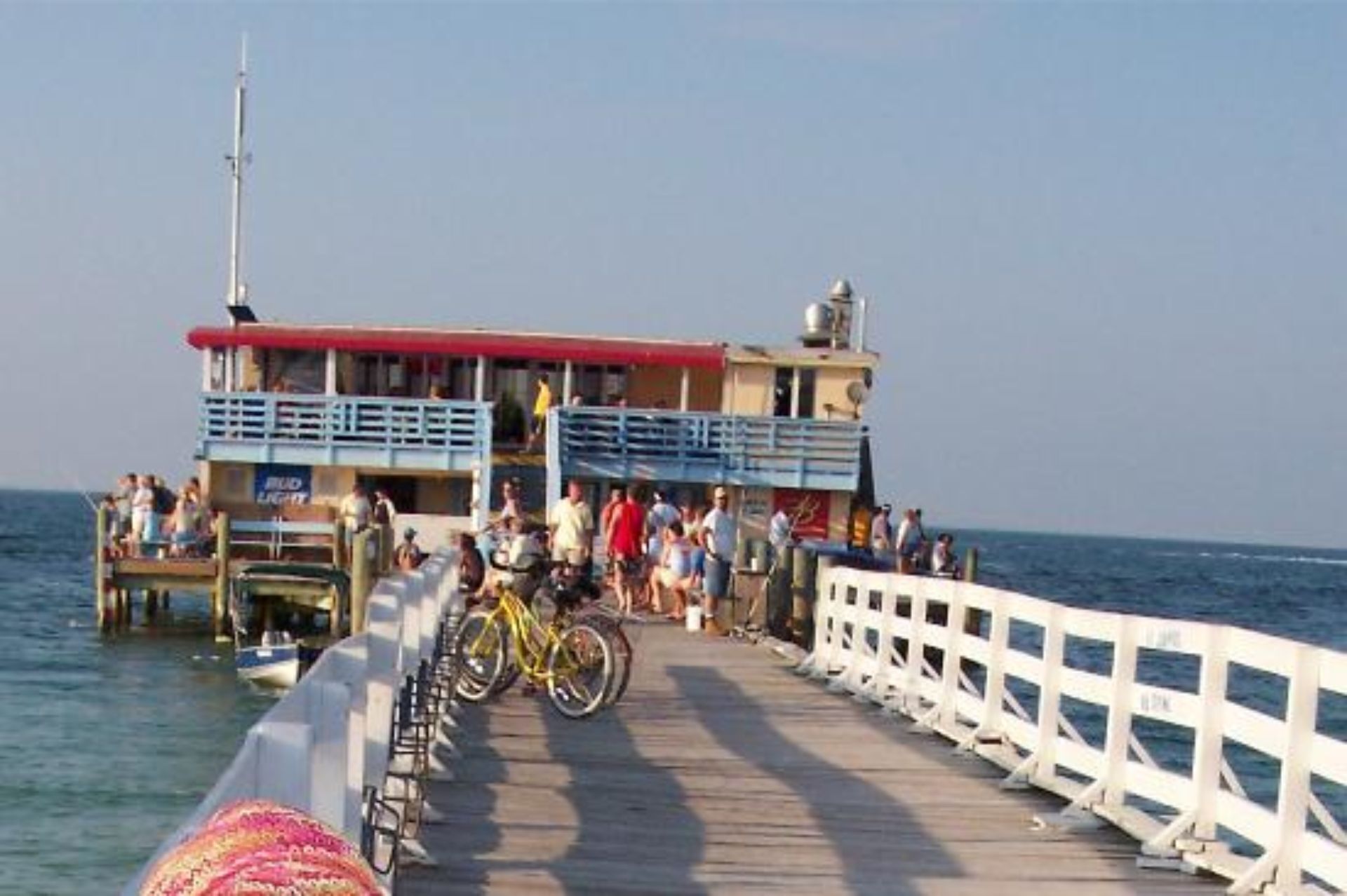 A pier with a building, bicycles, and people.