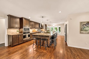 A modern kitchen with dark wood cabinets, stainless steel appliances, and a central island with bar stools.