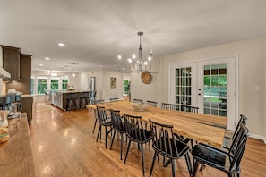 A spacious kitchen with a large island, wooden flooring, and modern lighting fixtures.