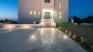 A modern two-story house with a concrete driveway, a front entrance with steps, and a small garden area. - Bianca Luxury Villa - Private Pool (Zakynthos)