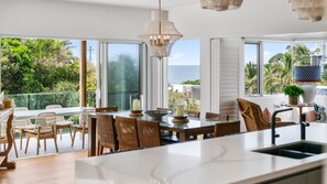 A modern kitchen with a large island, large windows, and a view of the ocean. - Surfside - 1min to the beach, ocean views w/heated swimming pool (Sunshine Beach)
