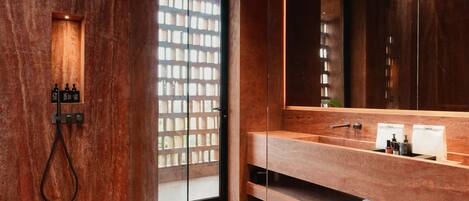 A modern bathroom with a wooden vanity, a large mirror, and a glass shower enclosure.