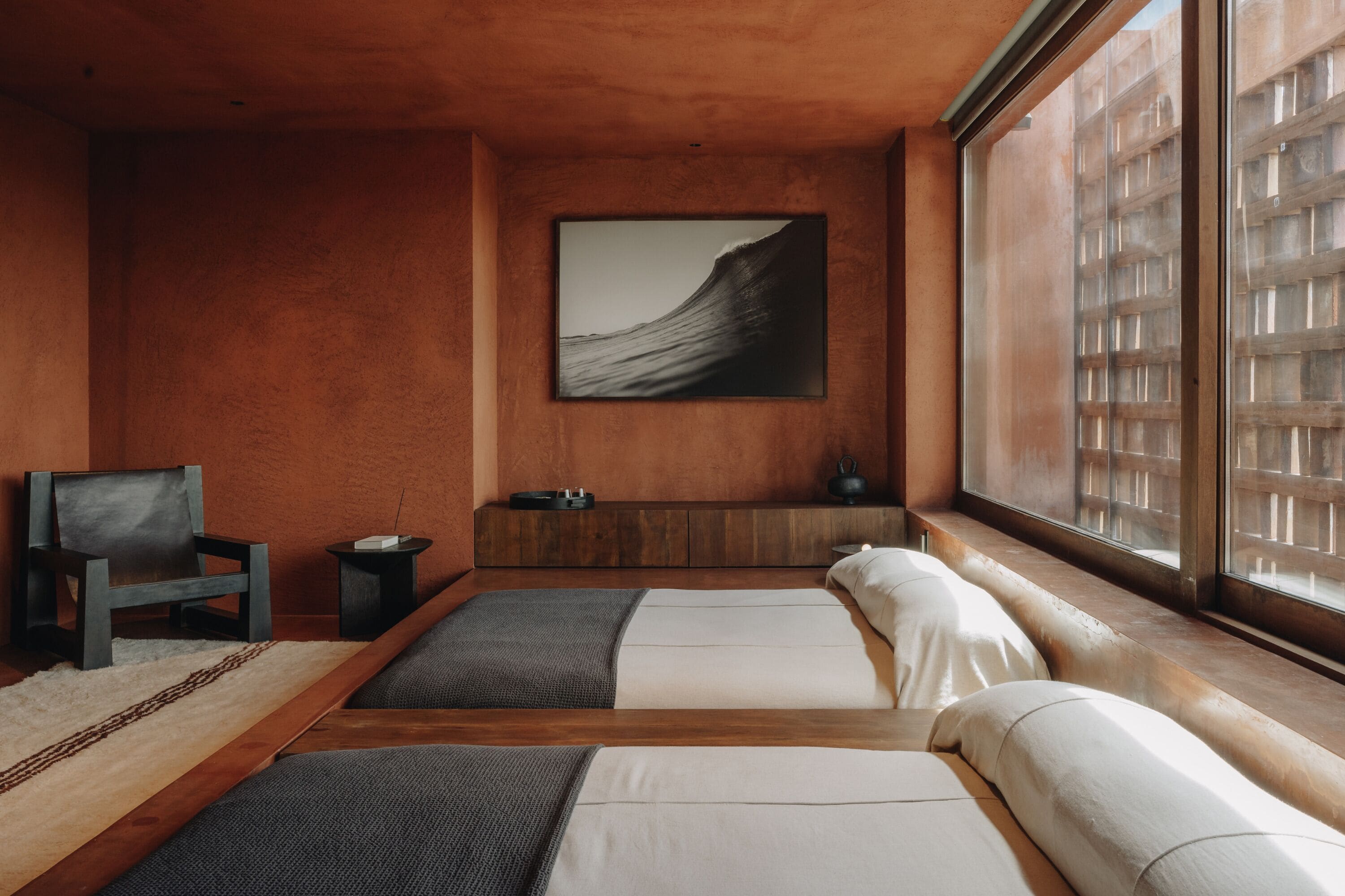 A modern room with two beds, a large window, and a framed artwork on the wall.