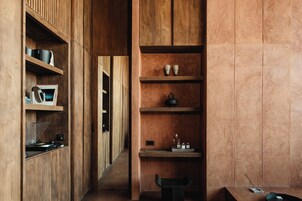 A narrow hallway with wooden shelving units on both sides, displaying various items like cups, a kettle, and a record player.