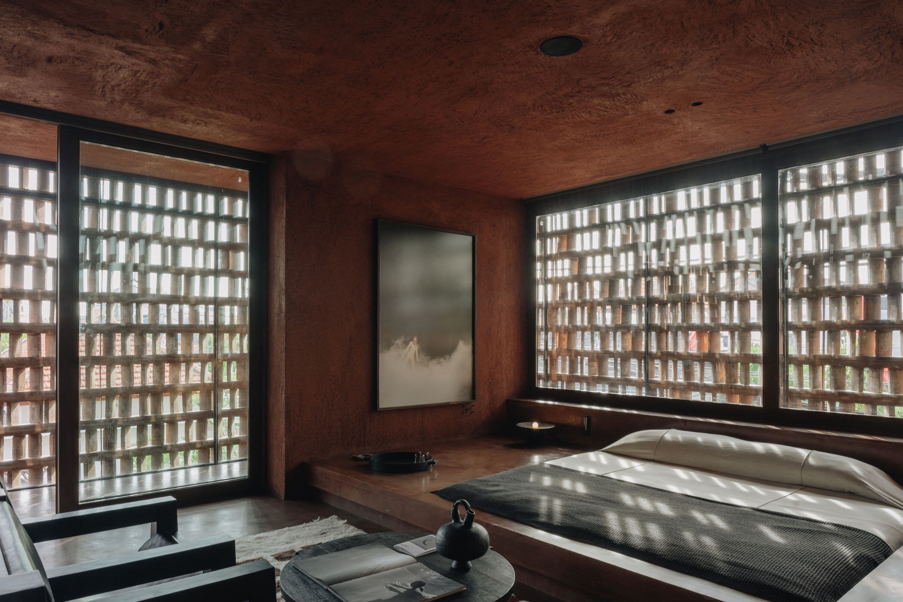 Una habitación con ventanas amplias, una cama, un hervidor de agua y un cuadro enmarcado en la pared.