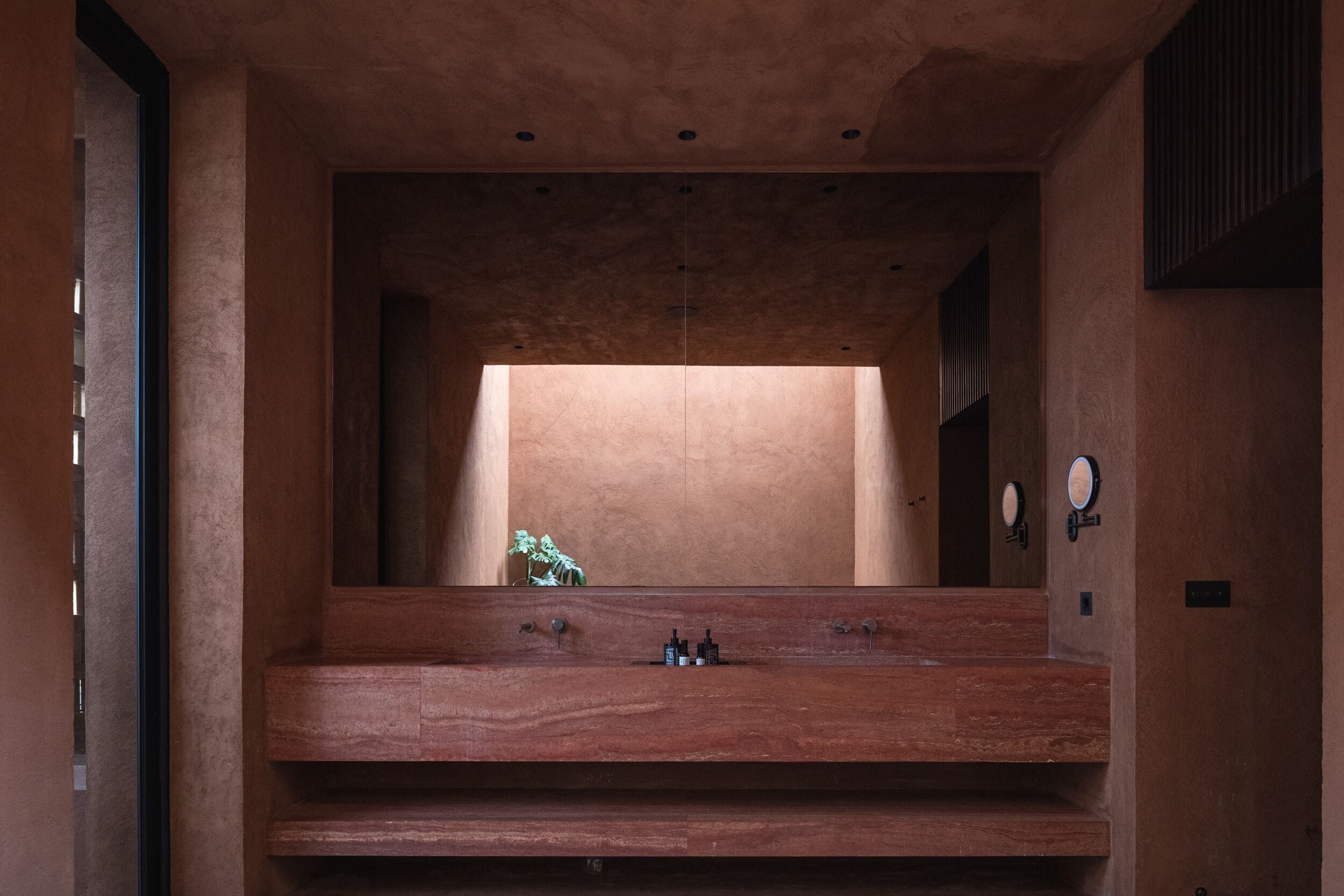 A modern bathroom with a wooden vanity, a mirror, and a small statue.