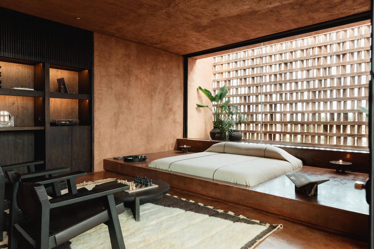 Une chambre à coucher moderne avec une grande fenêtre, un banc intégré, une table de chevet et une bibliothèque.