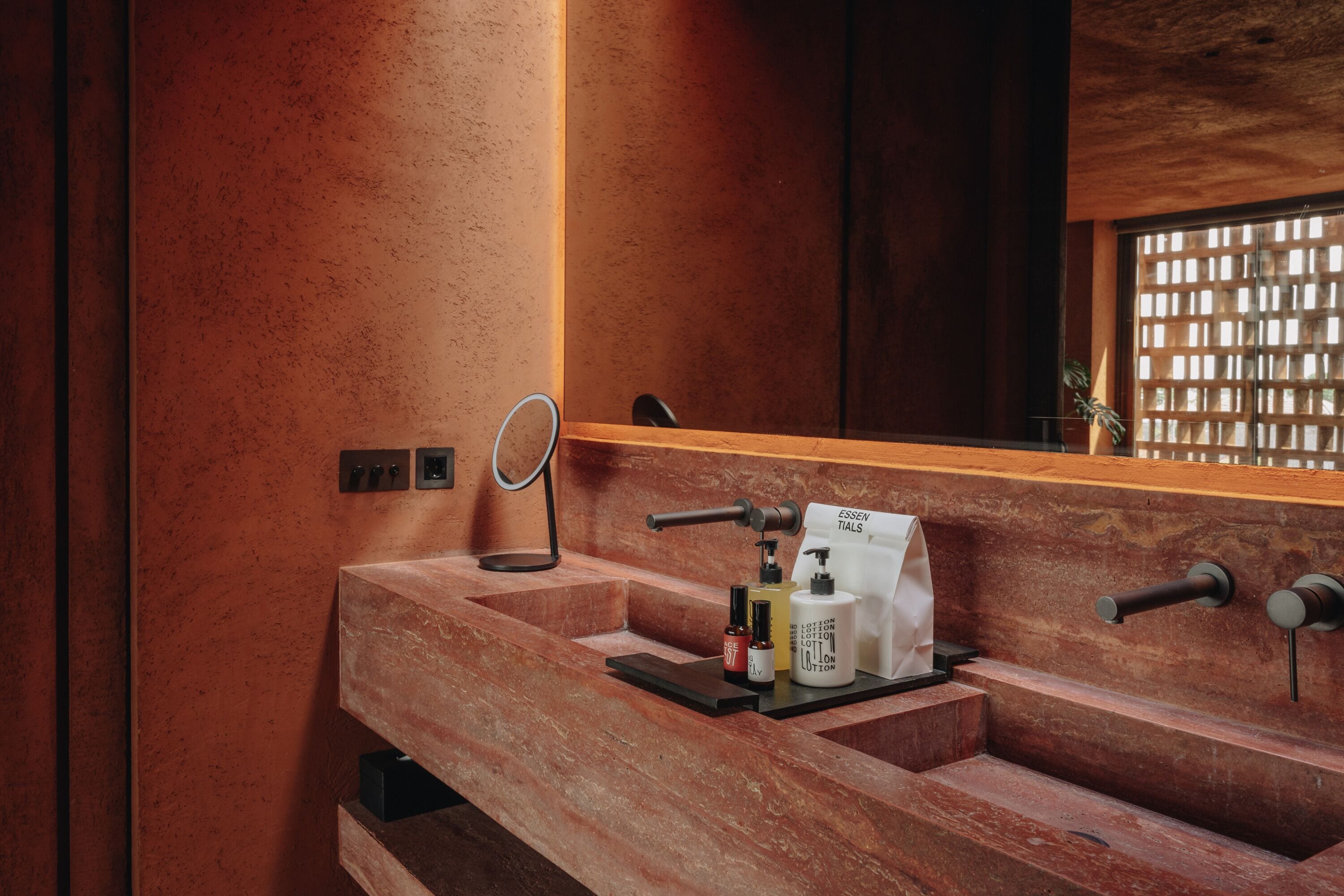 Un baño con tocador de madera, un espejo y artículos de aseo.