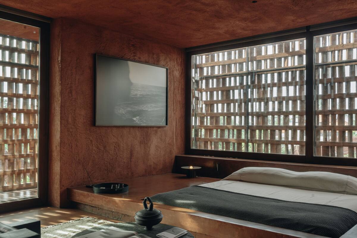Une pièce avec un lit, un tableau, une fenêtre donnant sur un beau paysage et une petite table avec une bougie.