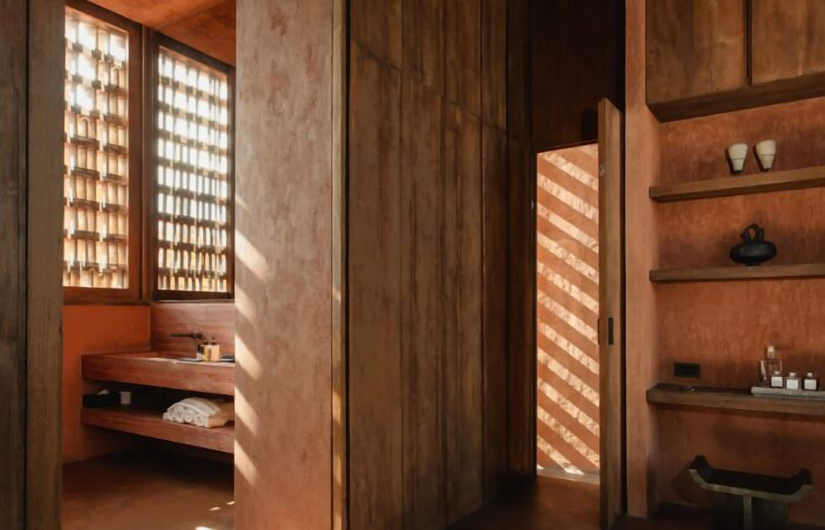 Un intérieur en bois avec un banc, des étagères et une fenêtre ornée d’un motif en treillis.