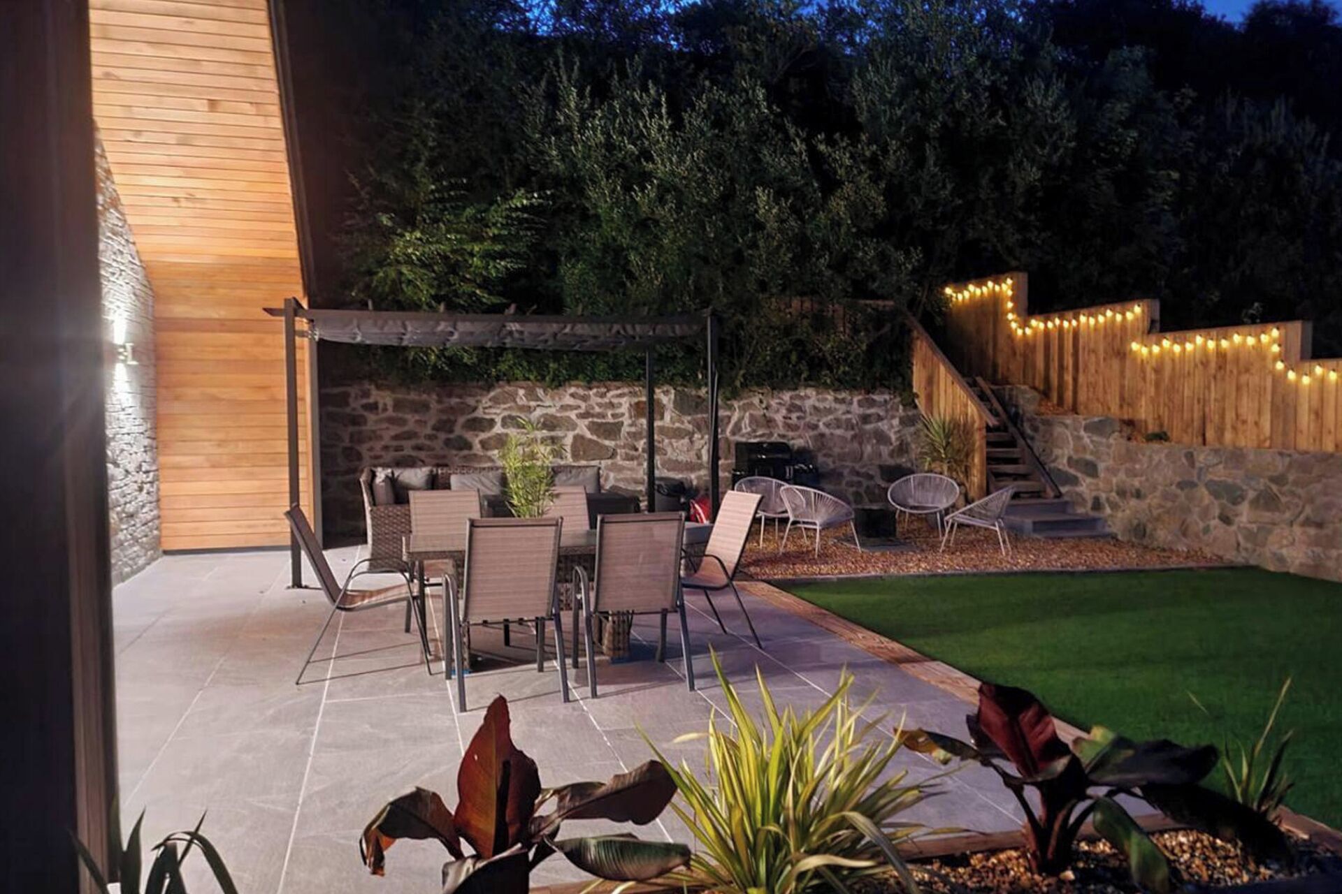 Un patio con mobiliario exterior, un muro de piedra y una terraza de madera.