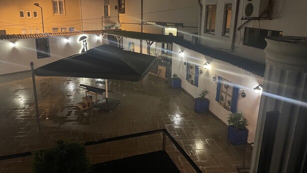 A courtyard with a covered seating area, potted plants, and a building with multiple windows and balconies. - Küçükağa Konağı (Aksehir)