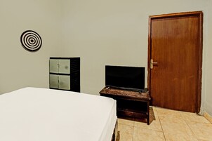 Una habitación de hotel con una cama, un televisor sobre un mueble de madera, un armario y una puerta.