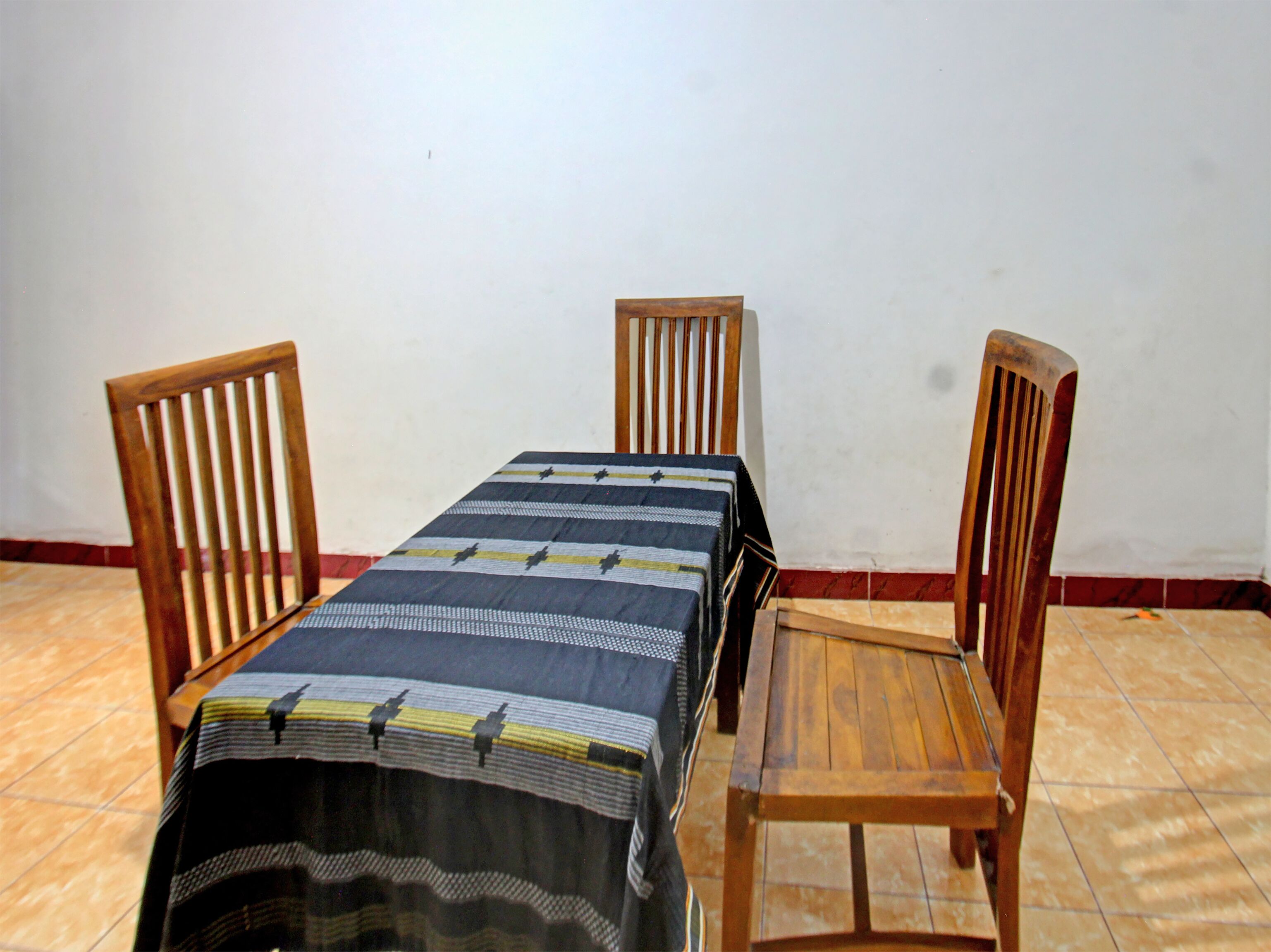 Una mesa de comedor con mantel a rayas, rodeada de cuatro sillas de madera.
