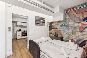 Ein modernes Zimmer mit einem Bett, einer kleinen Küchenzeile und einer farbenfrohen Ziegelwand.