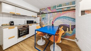 Una cucina con mobili bianchi, un tavolo blu e sedie arancioni.