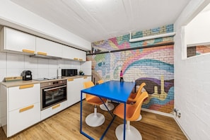 A kitchen with white cabinets, a blue table, and orange chairs.