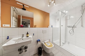 A modern bathroom with a white sink, a toilet, and a glass-enclosed shower.