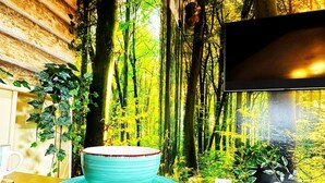 A cozy room with a wooden wall, a television, and a table with a blue mug and plates. - Squirrel Hideaway in Formby, Liverpool (Liverpool)