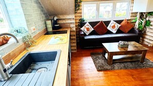 A cozy cabin interior with a wooden kitchen, a dining area, and a living room with a sofa and a coffee table. - Squirrel Hideaway in Formby, Liverpool (Liverpool)