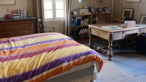 Ein Schlafzimmer mit einem Bett, einem Schreibtisch, einem Bücherregal und einem Fenster.