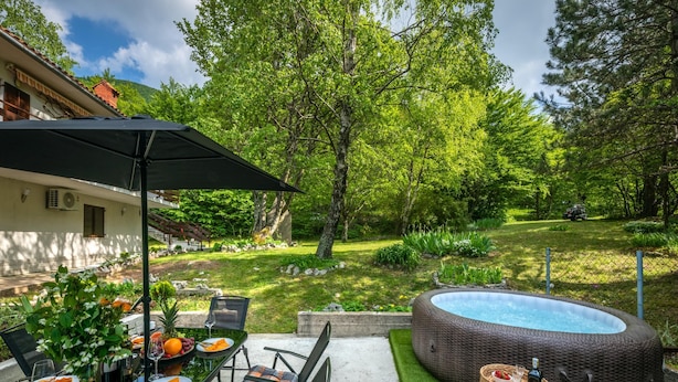 Une terrasse extérieure avec une table à manger, des chaises et un jacuzzi.