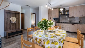Un espace repas moderne avec une table ronde, des chaises et un vase de fleurs.