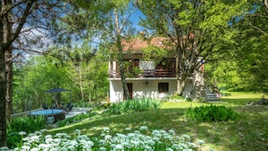 Une maison avec une piscine, entourée d’une végétation luxuriante et de fleurs blanches.
