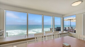 A dining area with a view of the ocean, large windows, and a wooden table. - Oceanfront 4BR | Private Beach | 2 Patios | BBQ (Oceanside)