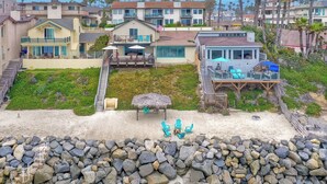 A coastal residential area with houses, a sandy beach, and a rocky shoreline. - Oceanfront 4BR | Private Beach | 2 Patios | BBQ (Oceanside)