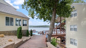 Sentiero di legno che conduce a un molo, con un cartello, una piscina e vista sul lago.