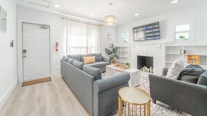 Ein modernes Wohnzimmer mit einem grauen Sofa, einem kleinen runden Tisch und einem Kamin.